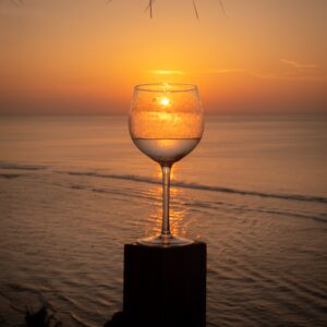 Weinglas im Sonnenuntergang am Strand