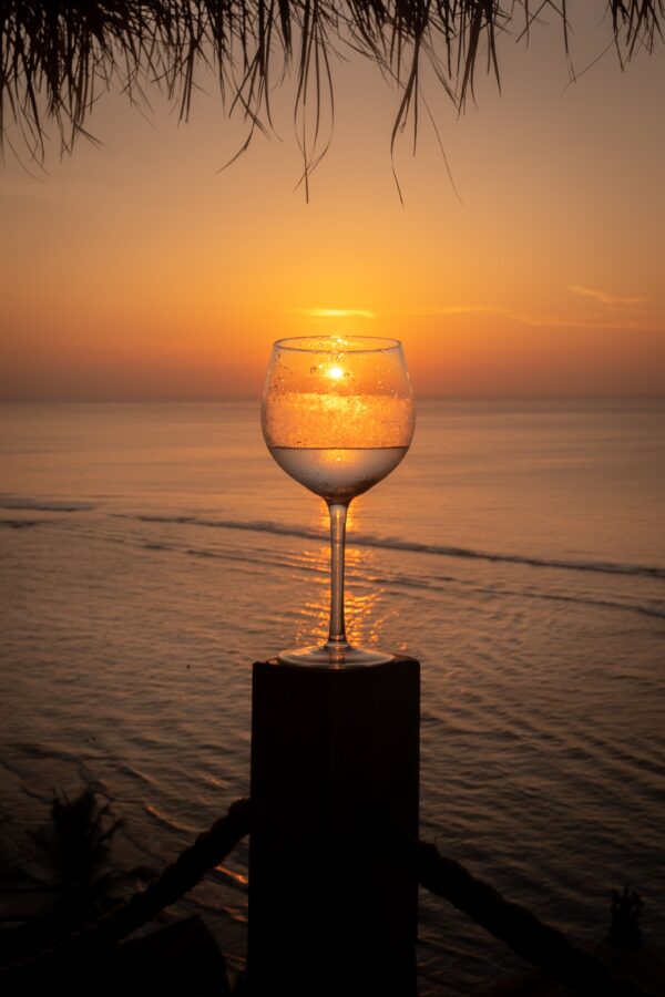 Weinglas im Sonnenuntergang am Strand