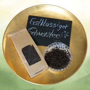 Darjeeling Tee BIO FTGFOP1 Packung mit Schale und Teeblättern auf einer goldenen Schale mit der Beschriftung "Erstklassiger Schwarztee"