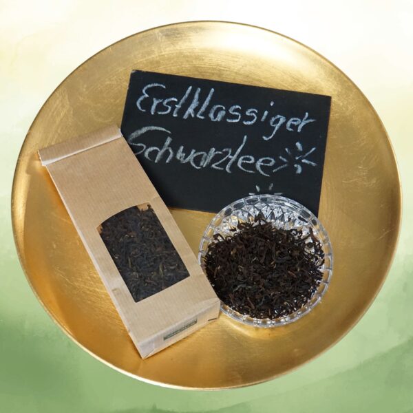 Darjeeling Tee BIO FTGFOP1 Packung mit Schale und Teeblättern auf einer goldenen Schale mit der Beschriftung "Erstklassiger Schwarztee"